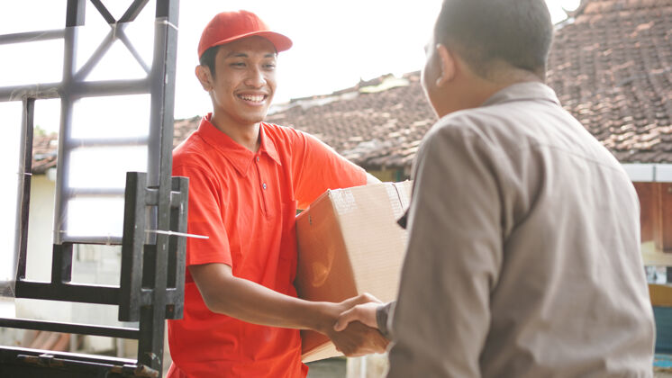 职业送货员把箱子交给顾客并握手男人送货快递