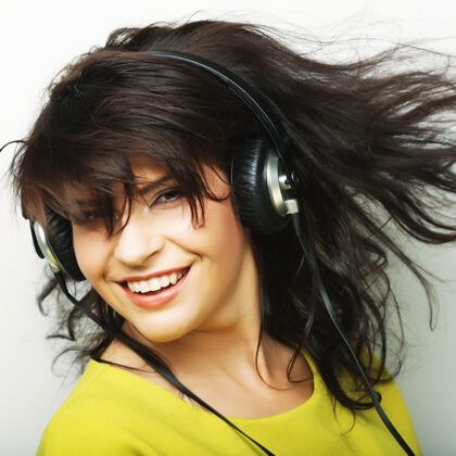 现代年轻快乐的女人戴着耳机听音乐可爱积极肖像