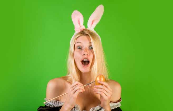 复活节背景性感的女人戴着兔子耳朵 手里拿着五颜六色的复活节彩蛋 在镜头前显得很惊讶兔子可爱兔子Promo