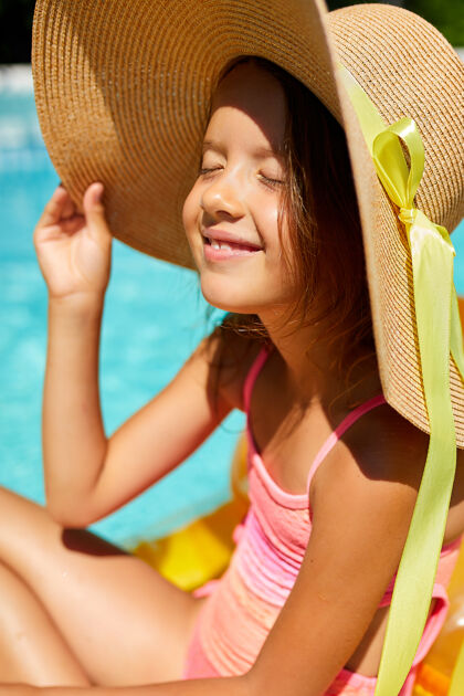 比基尼小女孩在游泳池里放松 坐在黄色充气床垫上晒太阳水夏天女性