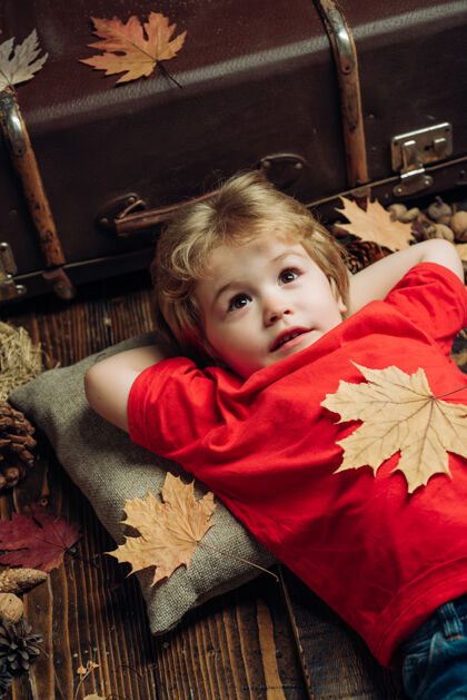 季节可爱的小男孩正在准备秋天金发碧眼小男孩趴在树叶上休息黑色销售博客趋势