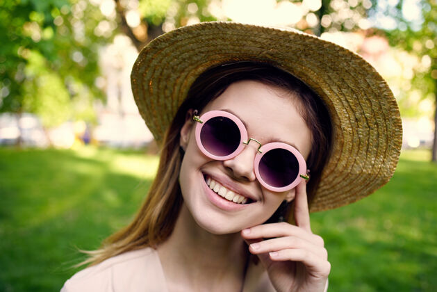 公园快乐的女人戴着帽子戴着墨镜在公园草地上散步女人自我学生