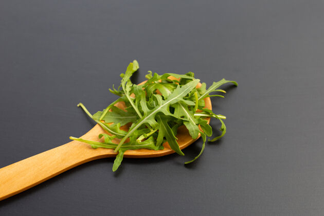 美味新鲜的绿色火箭沙拉在黑暗的表面上单一美食堆