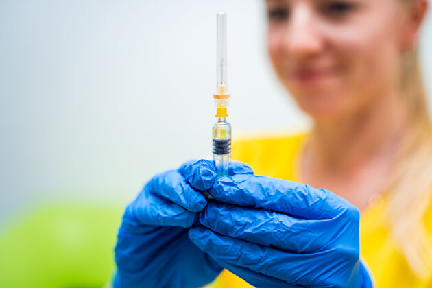 诊所医生或护士戴着蓝色手套 手里拿着装有婴儿或成人疫苗的注射器疫苗医学实验室