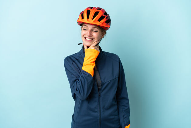 笑一个年轻的骑自行车的女人被隔离在蓝色的背景下 面带微笑地看着旁边快乐女人骑