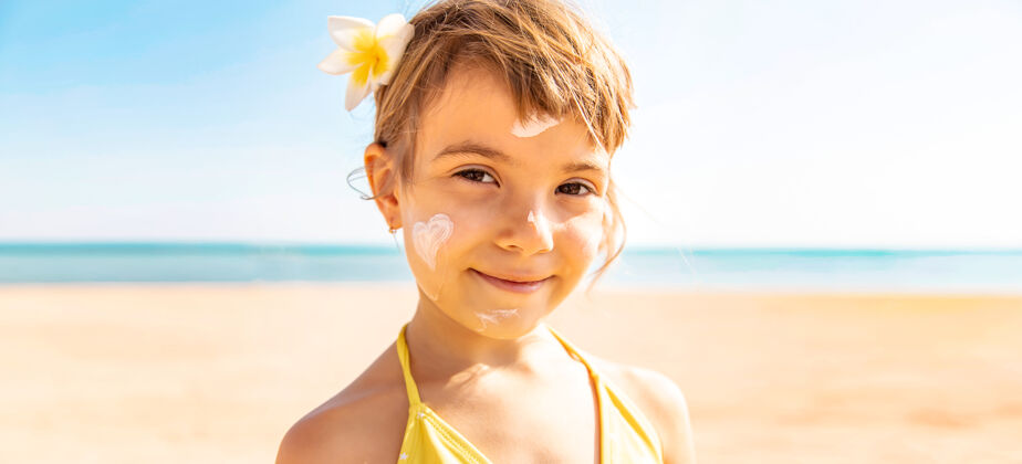 心小女孩在脸上涂防晒霜孩子海洋健康