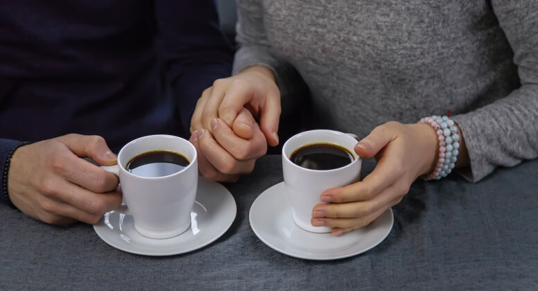 手一男一女端着一杯咖啡坐在桌边爱交流杯子