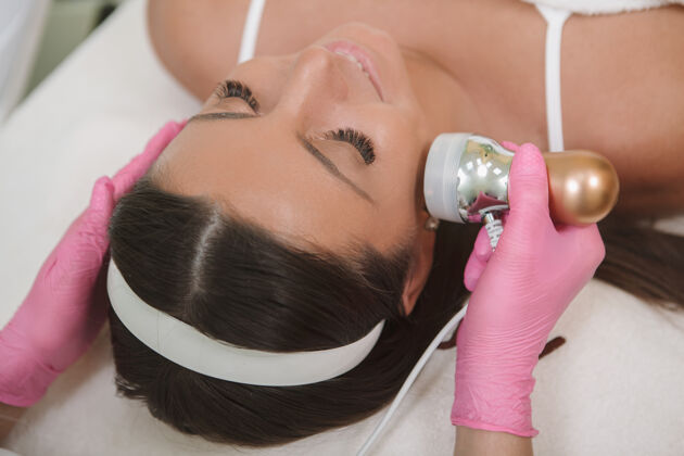 皮肤一个正在享受美容师的rf面部提升手术的女人清洁美容师帮宝适
