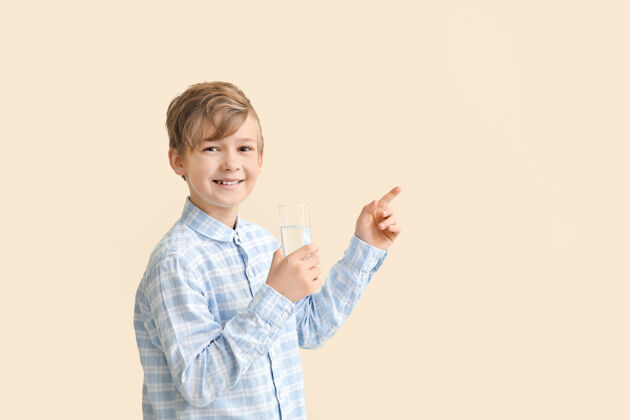 饮用可爱的小男孩拿着一杯水指着彩色的东西健康新鲜活力