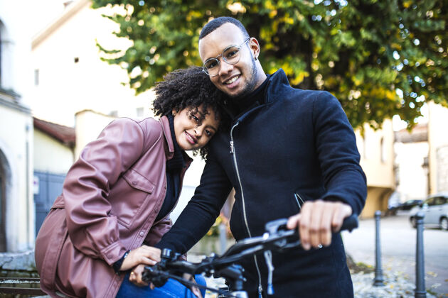 女孩坐在自行车上的幸福而知足的黑人夫妇背景度假旅游