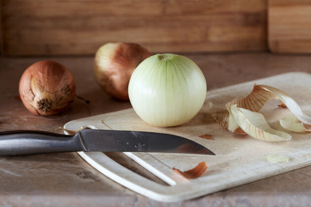 素食用刀把洋葱和洋葱皮放在餐桌的砧板上自然切片蔬菜