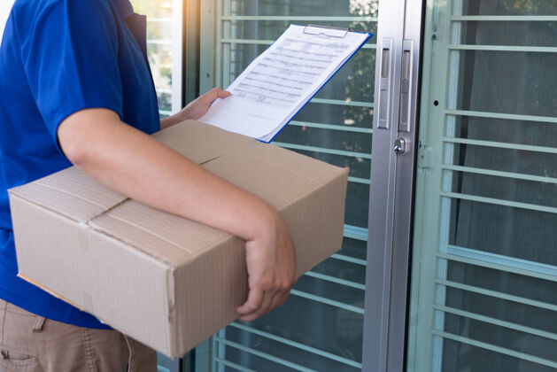 工人身穿蓝色制服的送货员为客户递包裹箱交货地址送货