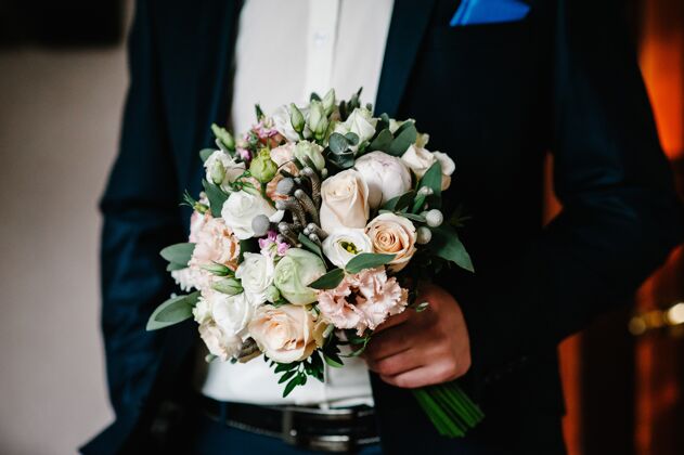 举行时髦的新郎正在举行婚礼婚礼花束花束在男人手里优雅时尚捆绑