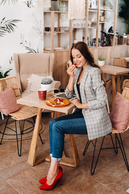 食物一个女人正坐在咖啡馆里吃草莓一个女孩手里拿着草莓在咖啡馆里甜味时尚早餐
