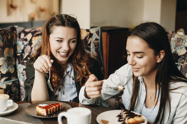 人两个可爱的女人坐在咖啡里吃蛋糕 而故事特灵微笑着玩得很开心食物女性甜点