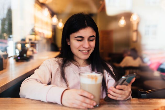 咖啡馆女孩微笑着 在咖啡馆喝咖啡 看书电话模糊背景高高质量的照片模糊饮料桌子