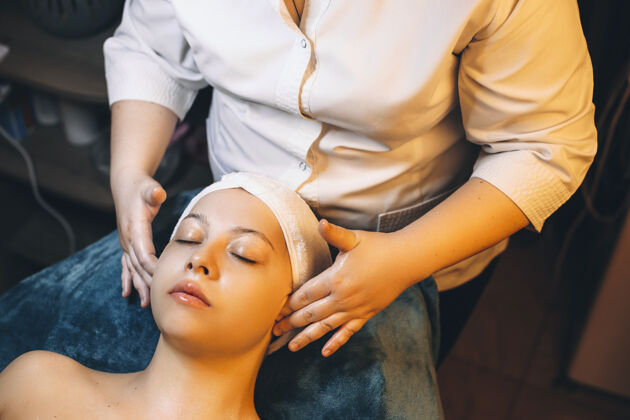 美容师上图是一位美容师用手在女性脸上做面膜后的面部按摩治疗美容完美