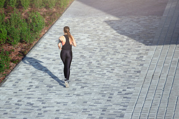 运动穿着运动服的女人在城市的灰色人行道上奔跑身体运动私人教练