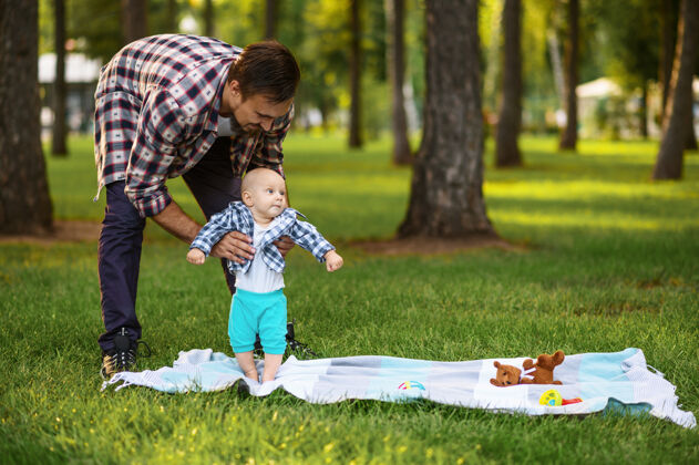 公园快乐的父母和小宝宝在夏日公园的草地上玩耍假期草人