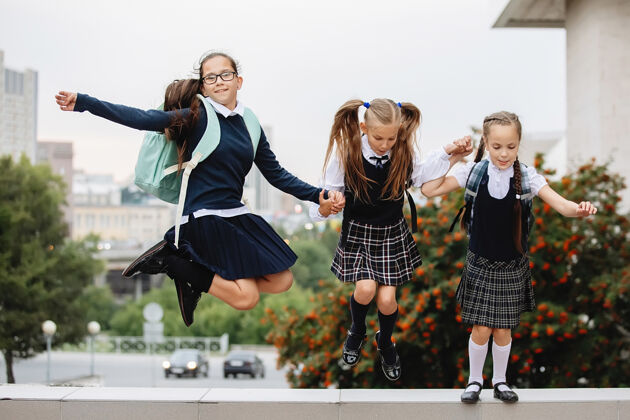 友谊三个穿制服的女学生跳起来大笑起来朋友童年水平