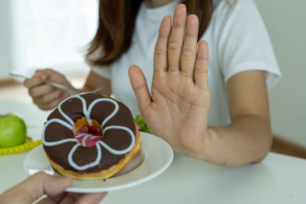 饮食女人们过去常常用手推甜甜圈盘子人做什么不要为了减肥而吃甜点甜巧克力脂肪超重