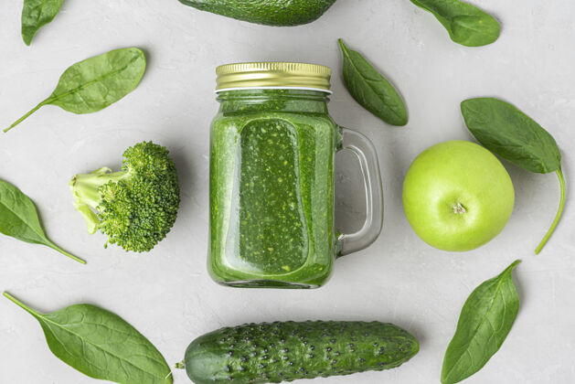 新鲜用菠菜 花椰菜 鳄梨 苹果和蔬菜做成的健康的绿色冰沙黄瓜上衣视图.平面生的纯素食物概念排毒平躺健康