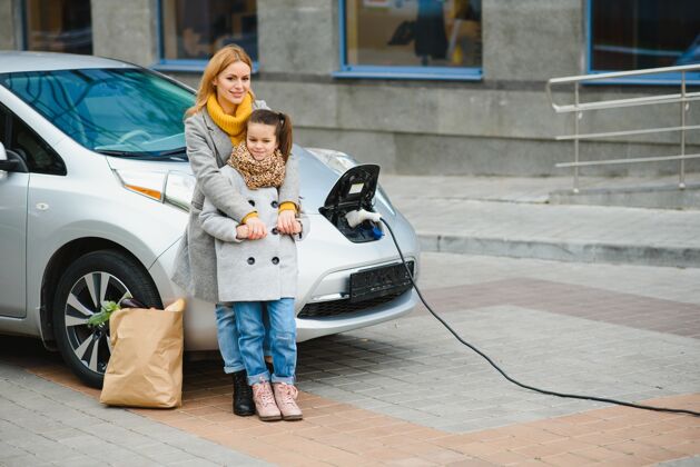 驾驶员时尚母女为电动车充电 共度时光妇女充电器母亲