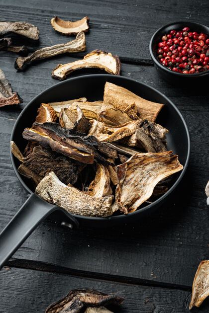 平底锅把切碎的野生干蘑菇放在铸铁煎锅里 放在黑木桌的背景上意大利配料森林