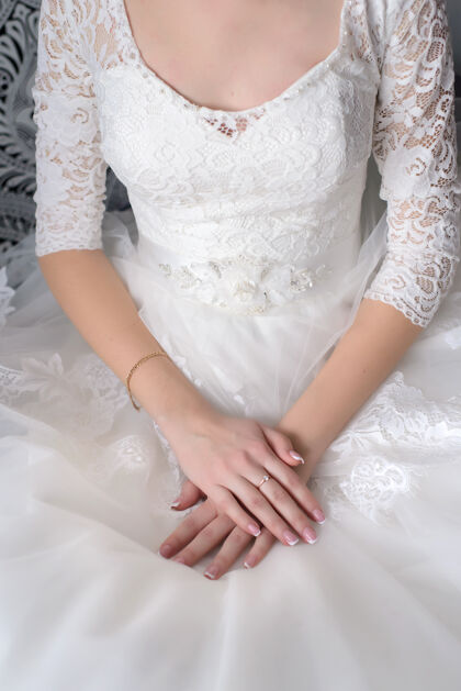 女人新娘把她娇嫩的手叠在一件白色漂亮的裙子上人手指女孩