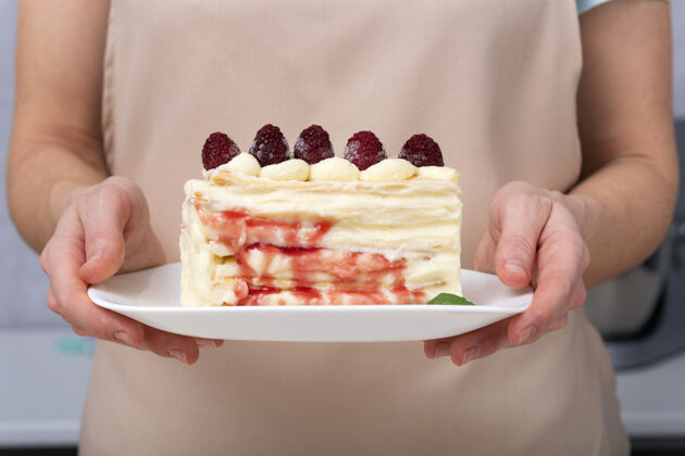 室内女性茶碟上的水果蛋糕手关上上一块草莓奶油馅饼蛋糕美味香草片
