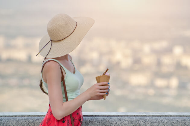成人戴帽子的女孩手里拿着冰激凌 从高处看着城市旅行户外女孩