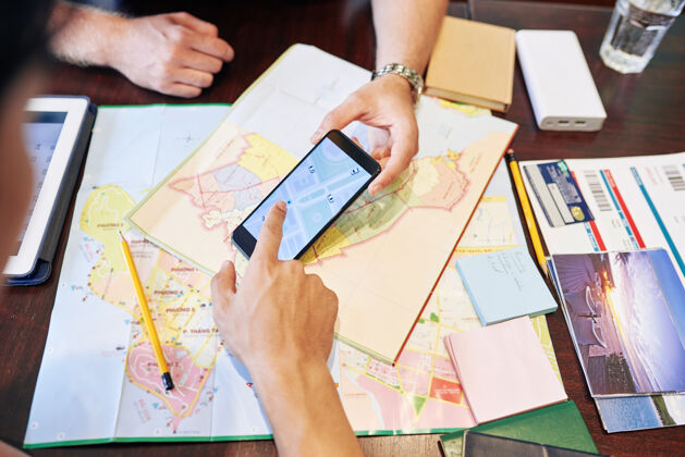 公路旅行在计划海上公路旅行时 朋友在智能手机上查看地图的特写图片合作桌子度假