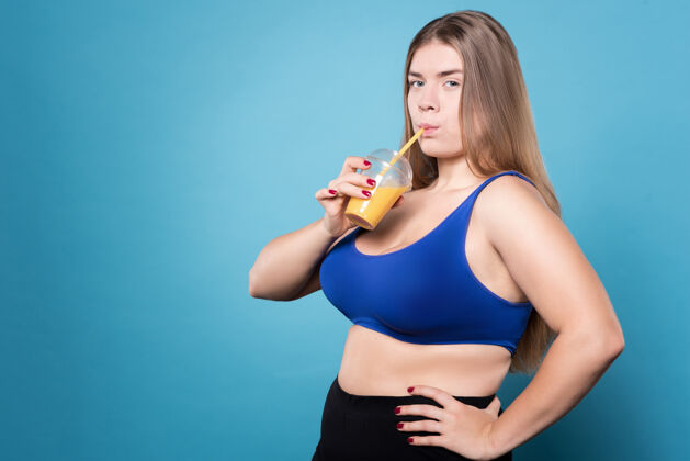 胖乎乎的享受健康饮食超重女人喝着橙汁 胳膊放在臀部上女士超重运动