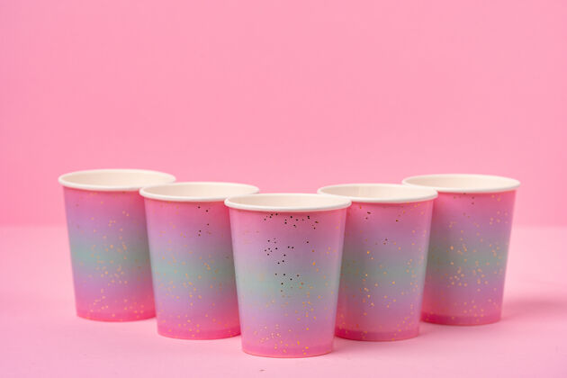 庆祝粉红色背景上的粉红色一次性纸杯容器明亮背景
