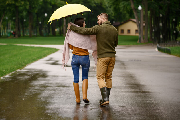 拥抱情侣在公园喝热咖啡 夏天下雨戴曼雨中的女人站在雨伞下 漫步小径上的浪漫约会 小巷里的潮湿天气团聚夫妇男性
