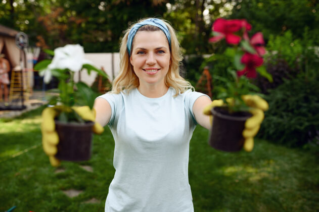 耙子一个女人在花园的花盆里展示两朵花花园女园丁照顾植物户外 园艺爱好 花店的生活方式和休闲设备活动农场