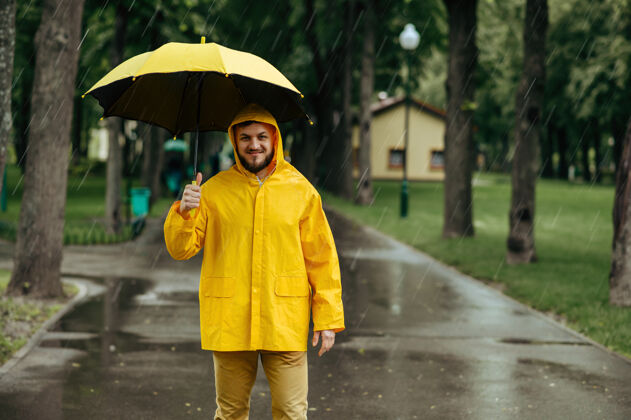 巷子雨中带伞的人在公园散步白天男性穿着雨衣和胶靴的人 潮湿的天气雨滴气候徒步旅行