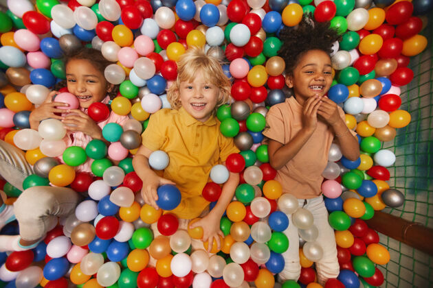 人一群快乐的孩子们躺在水池里的彩球中间 面带微笑童年室内球