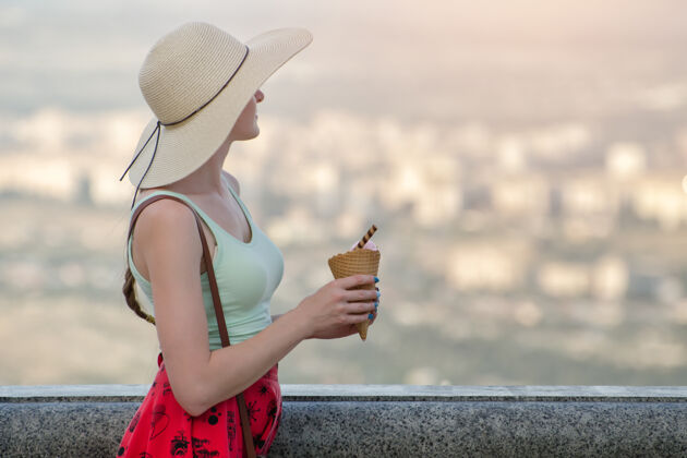 女人戴帽子的女孩手里拿着冰激凌 从高处看着城市女性风景女孩