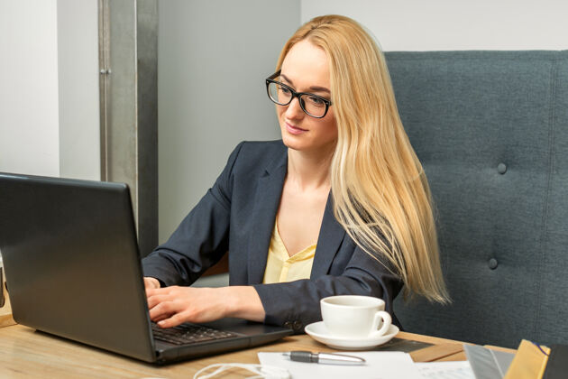 无线年轻的女商人坐在咖啡馆的桌子旁用笔记本电脑吸引力女智能