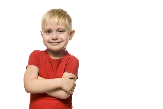 自信微笑的金发小男孩穿着红色t恤 站在折叠的椅子上手臂隔离白色背景年轻姿势休闲