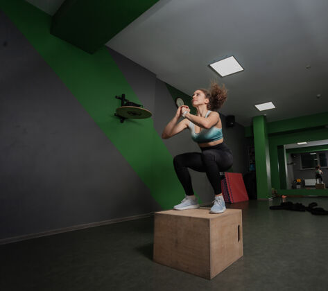 动机在一场运动会上 一个年轻健康的女人在木箱上跳跃功能类训练 锻炼跳跃女性训练