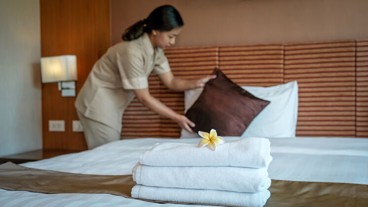 员工普洛玛丽亚和毛巾摆在酒店女佣面前 在豪华酒店房间里整理床铺 为游客出行做好准备女性枕头客房