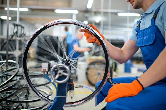 维修机床上的男工人正在检查自行车的轮辋工厂自行车车轮装配车间 自行车配件安装铝车间齿轮