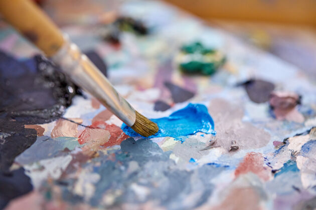 绘画特写照片的彩色颜料调色板在艺术工作室 艺术家混合绘画颜料在画布上油漆画布刷子