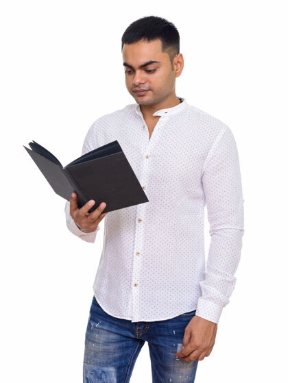印度年轻英俊的印度男人正在读一本与空白隔离的书20多岁男性吸引力