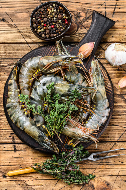 巨人生黑虎虾虾在切菜板上与草药甲壳类动物海洋贝壳