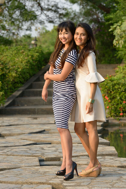 拍摄两位亚洲年轻女性在公园户外放松的写真泰国情侣和平