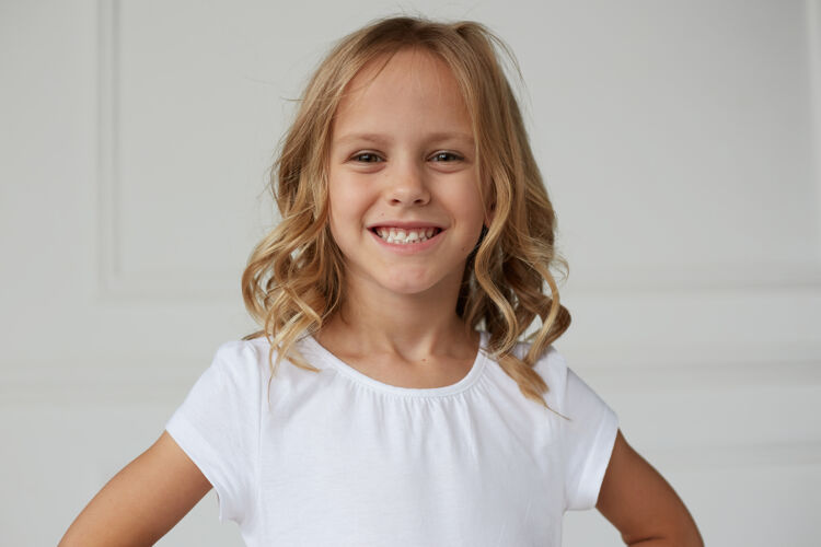 姿势一个可爱的微笑的小女孩展示她的牙齿嚼口香糖的特写镜头年轻小金发