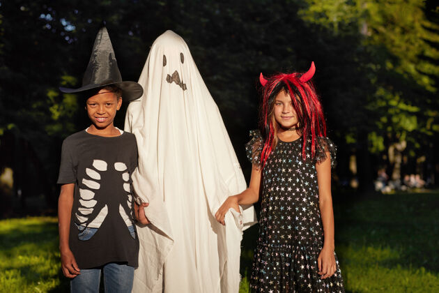 衣服万圣节户外派对上 身着女巫和鬼魂服装的孩子们对着镜头微笑的画像舞台服装巫师孩子